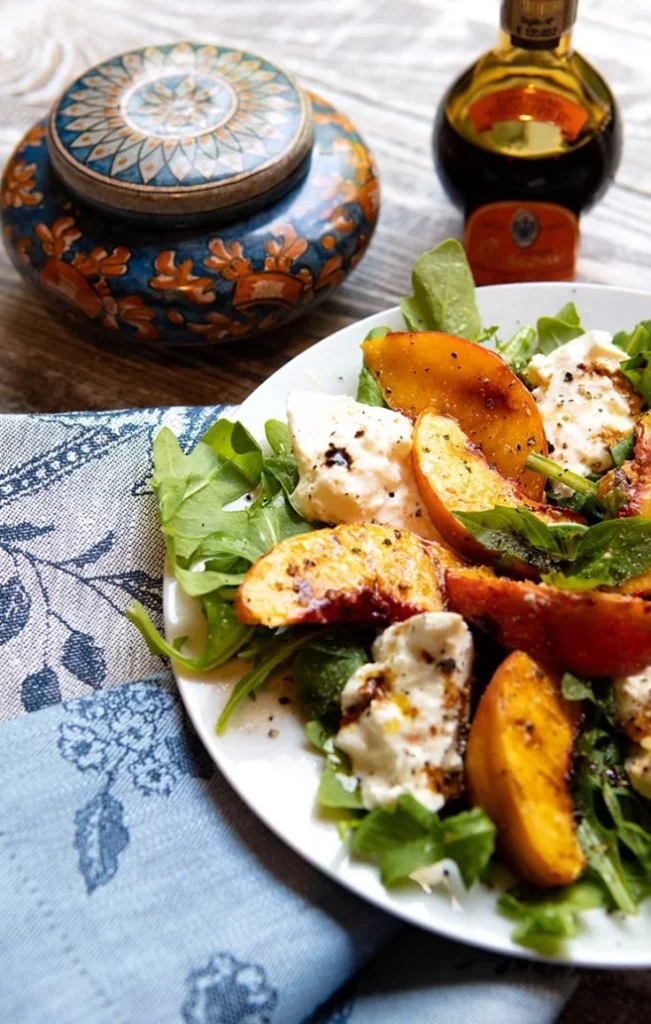 Grilled Peach & Burrata Salad garnished with fresh herbs and greens