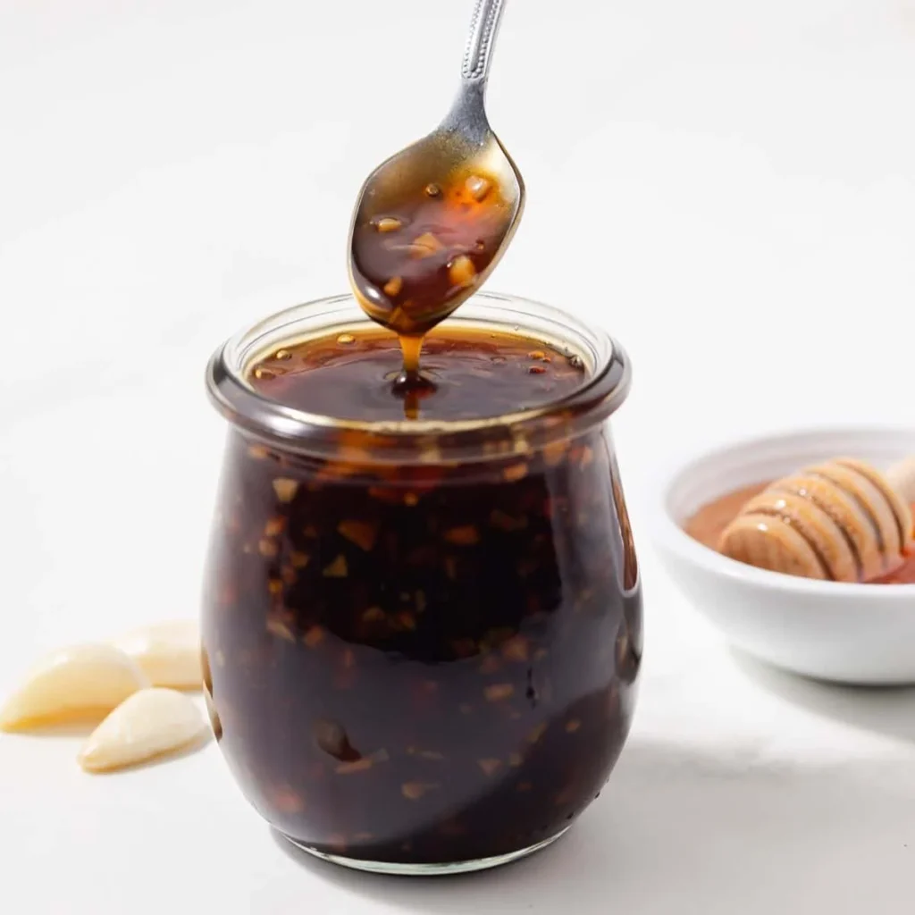 Delicious homemade honey garlic sauce in a glass jar with fresh garlic and honey.