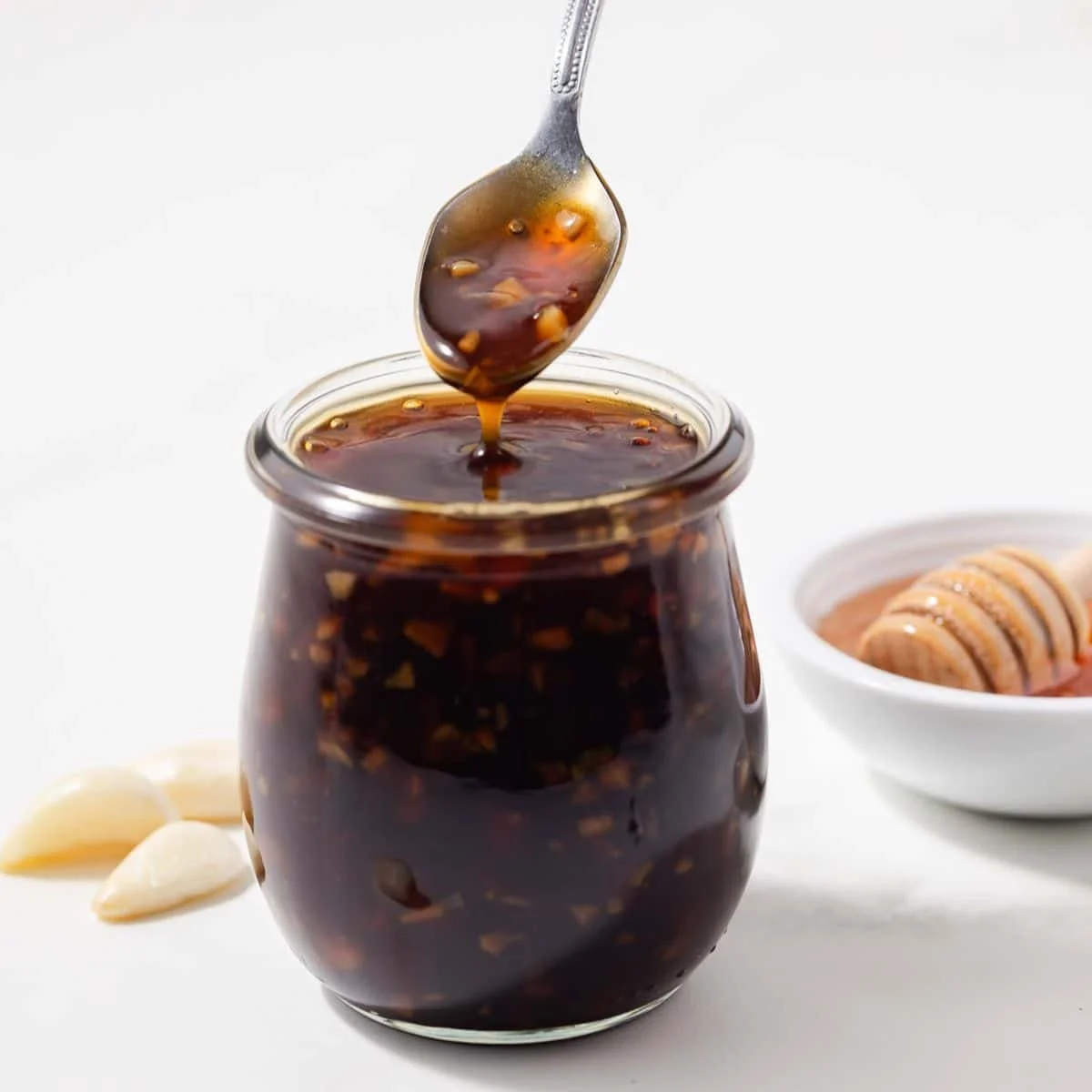 Delicious homemade honey garlic sauce in a glass jar with fresh garlic and honey.