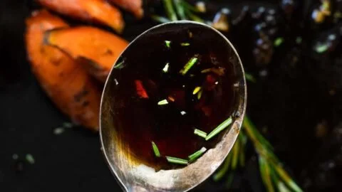 Homemade honey garlic sauce in a glass jar with garlic cloves and honey drizzled around.