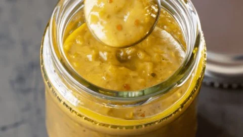 Jalapeño honey mustard sauce in a bowl with drizzled honey and sliced jalapeños