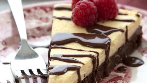 Delicious Keto Brownie Cheesecake topped with chocolate ganache and nuts