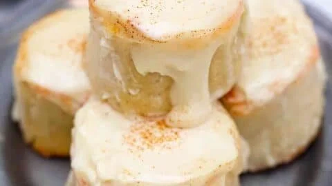 Delicious keto cinnamon rolls topped with cream cheese icing on a wooden table