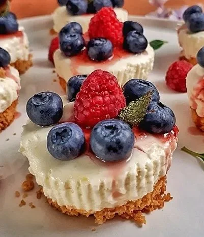 Delicious keto mini cheesecakes topped with fresh berries and whipped cream.