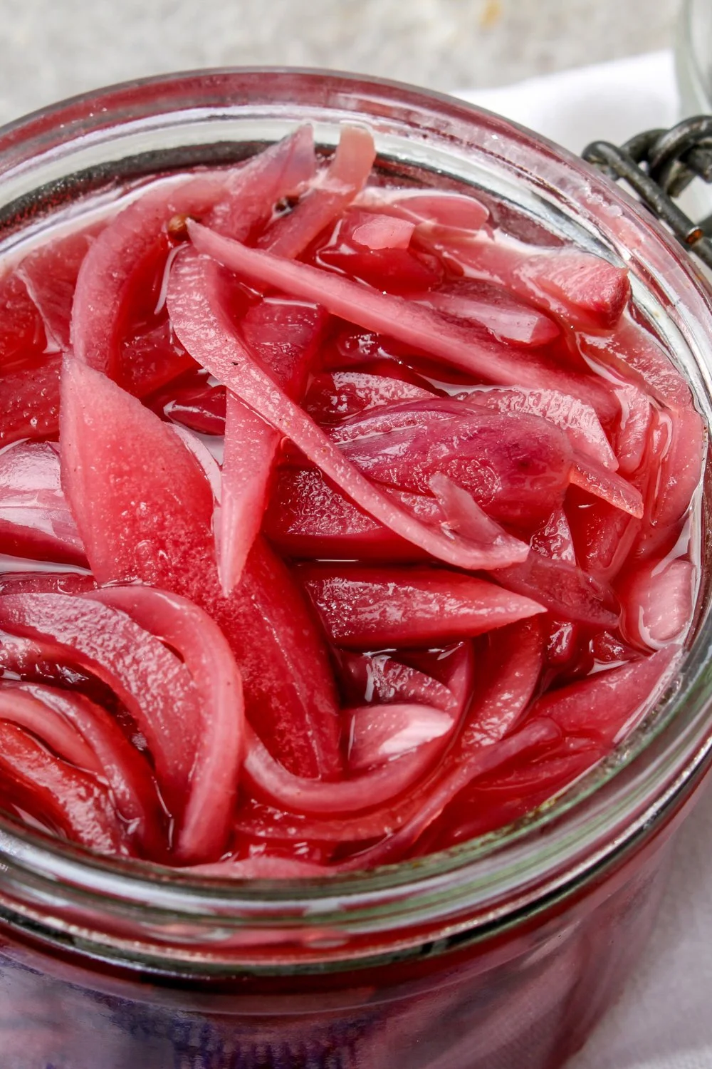 Homemade pickled onions in a glass jar with fresh herbs