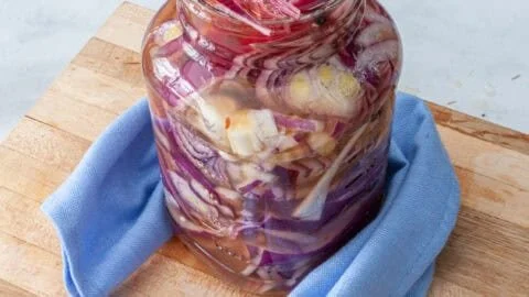Jar of homemade pickled onions with vibrant color and spices