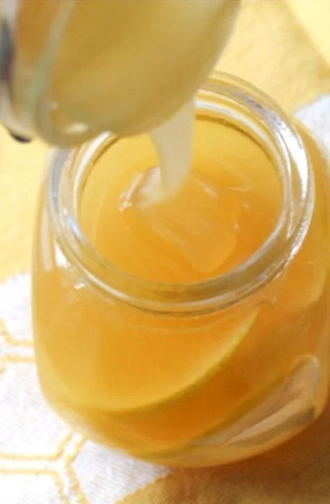 Homemade honey lemon cough syrup in a jar with lemon and honey ingredients
