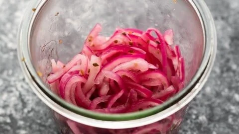 Jar of quick pickled red onions on a kitchen counter