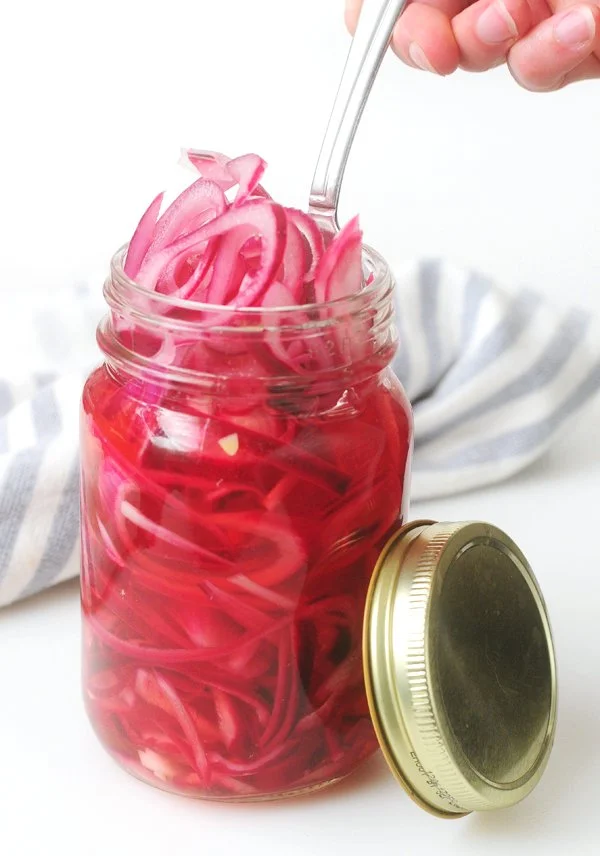 Bowl of quick pickled red onions with vibrant colors and spices