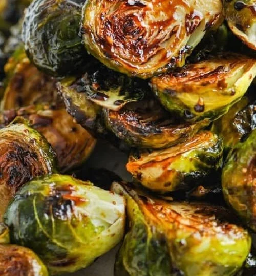 Plate of roasted balsamic Brussels sprouts garnished with herbs