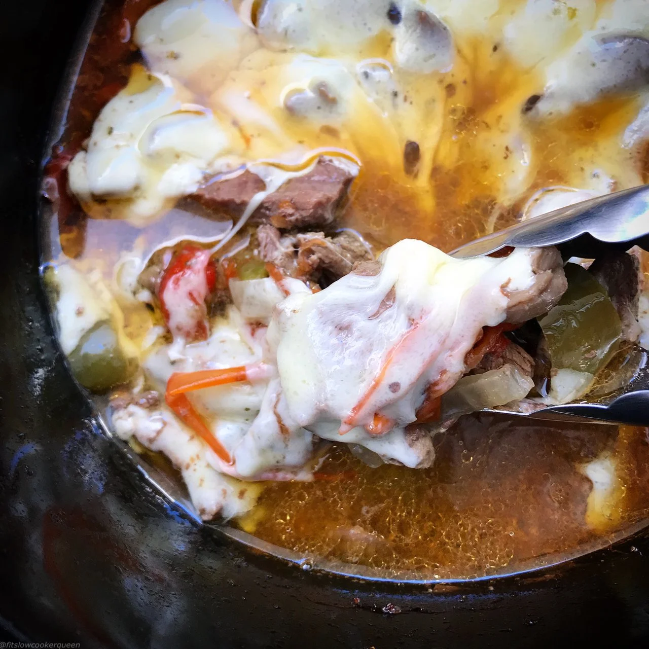 Slow cooker cheesesteaks served on a plate with toppings