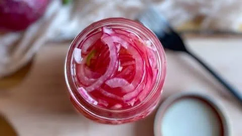 Homemade spicy pickled onions in a jar, ready to enhance your dishes.