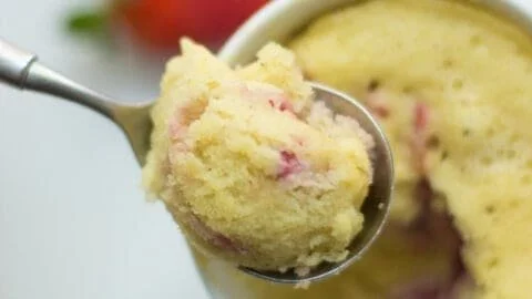 Strawberry almond flour mug cake served in a white mug with fresh strawberries