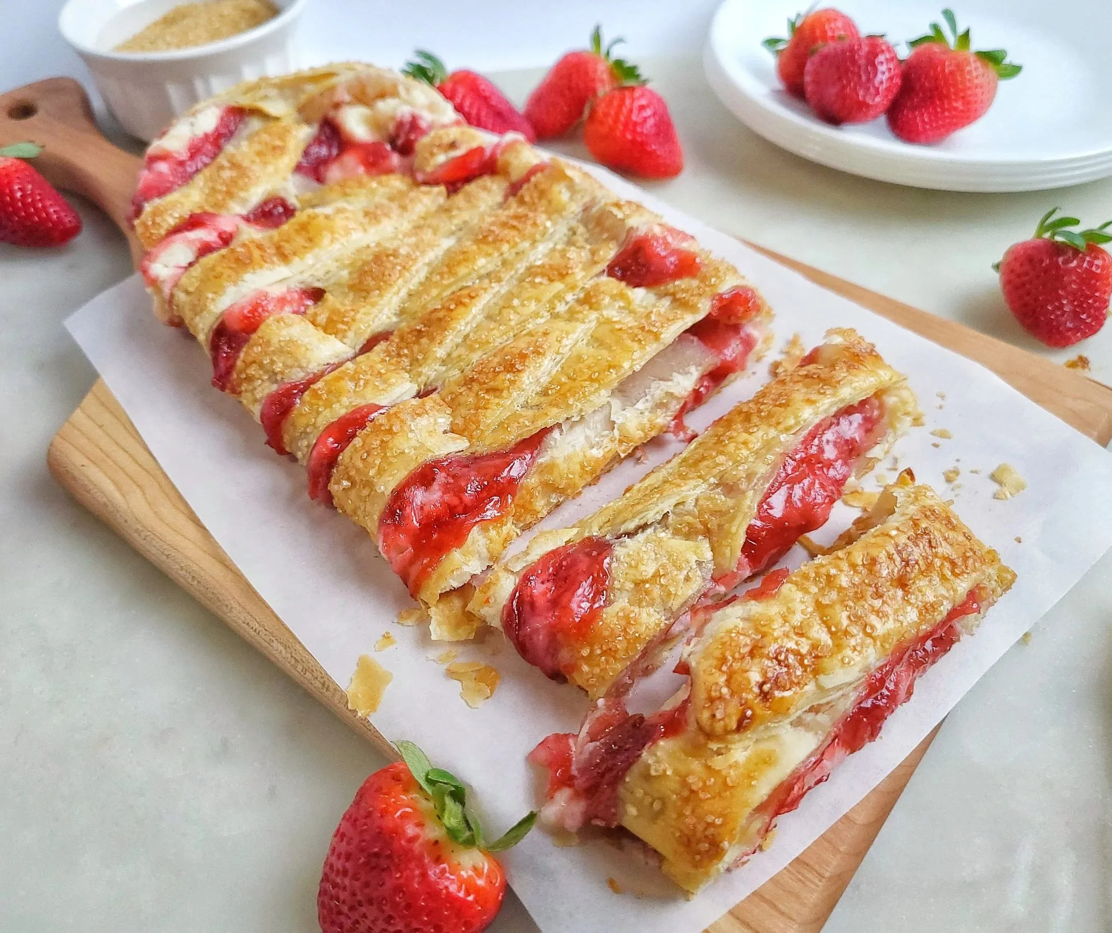 Freshly baked Strawberry Strudel with cream cheese filling on a plate.