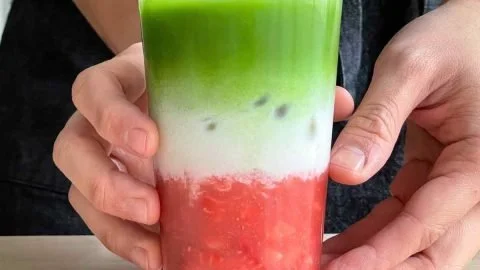 Strawberry Matcha Latte in a glass topped with fresh strawberries