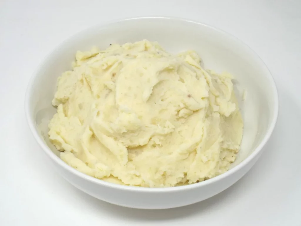 Bowl of creamy classic mashed potatoes with butter and herbs