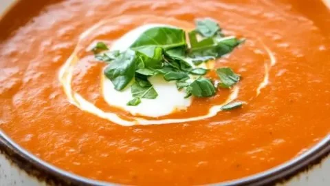 Bowl of creamy tomato bisque soup garnished with fresh basil