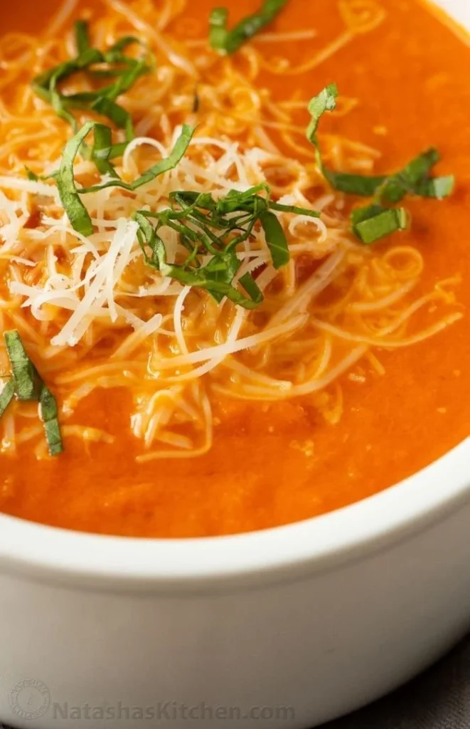 Bowl of creamy tomato soup garnished with fresh basil leaves