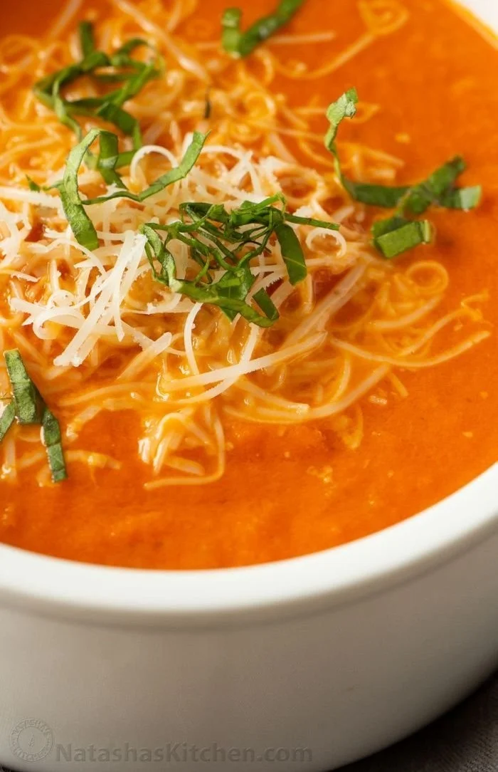 Bowl of creamy tomato soup garnished with fresh basil leaves