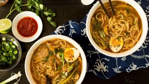 Bowl of easy chicken ramen garnished with green onions and eggs.
