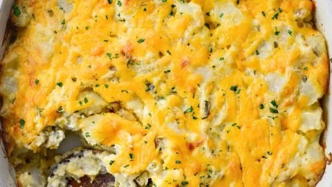 Baked homemade cheesy potatoes topped with melted cheese and herbs
