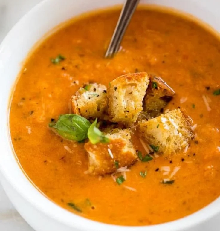 Bowl of homemade Tomato Basil Soup garnished with fresh basil leaves.