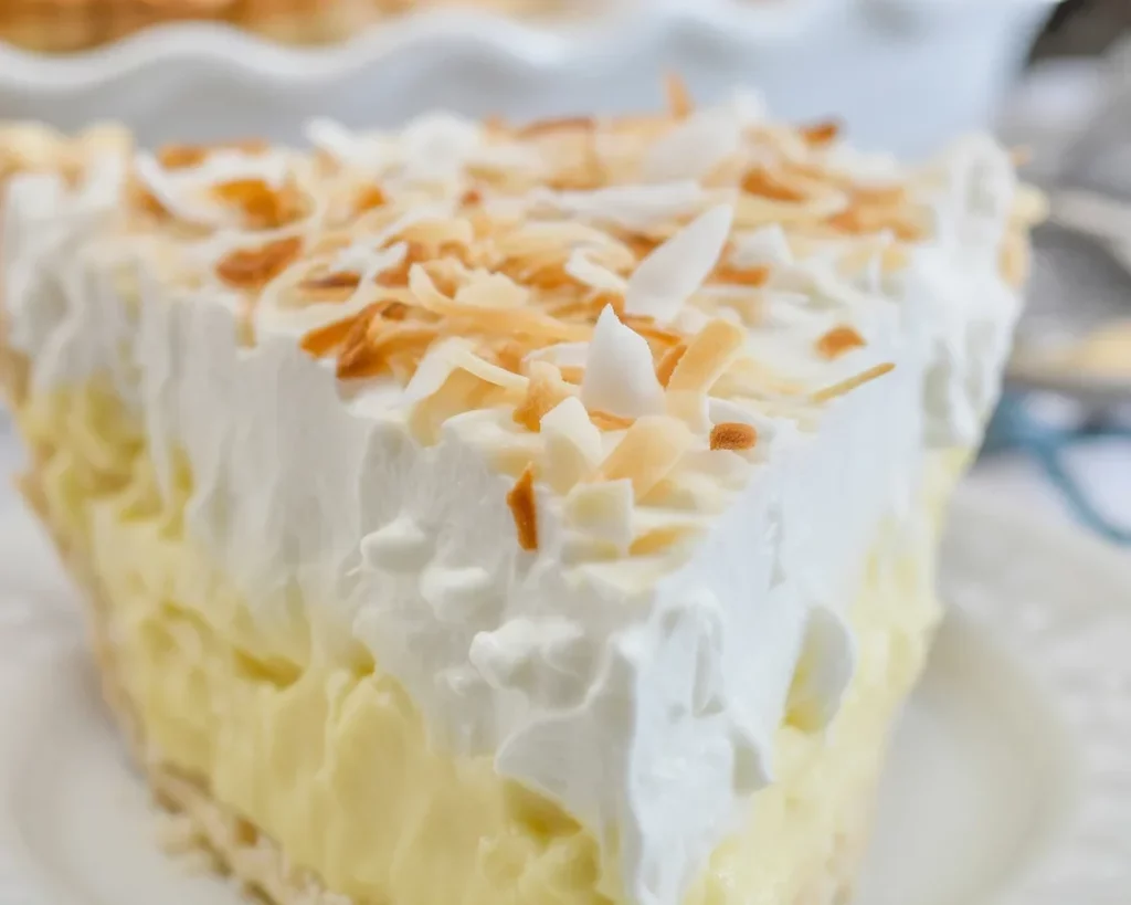 A slice of Grandma's homemade coconut cream pie topped with whipped cream and toasted coconut.