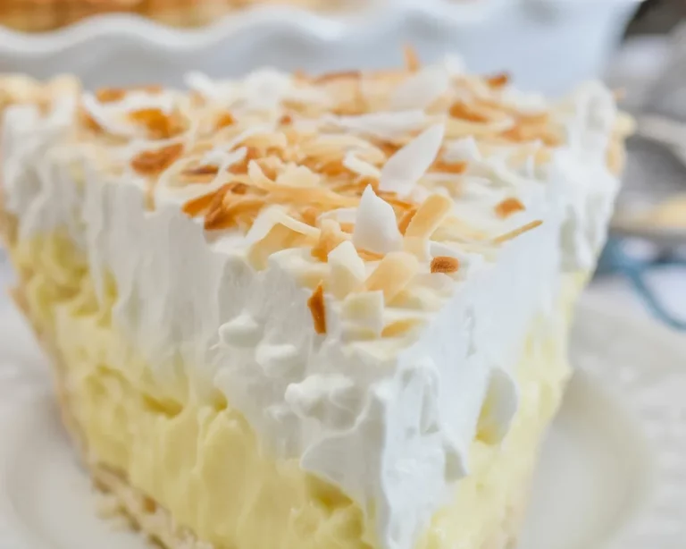 A slice of Grandma's homemade coconut cream pie topped with whipped cream and toasted coconut.