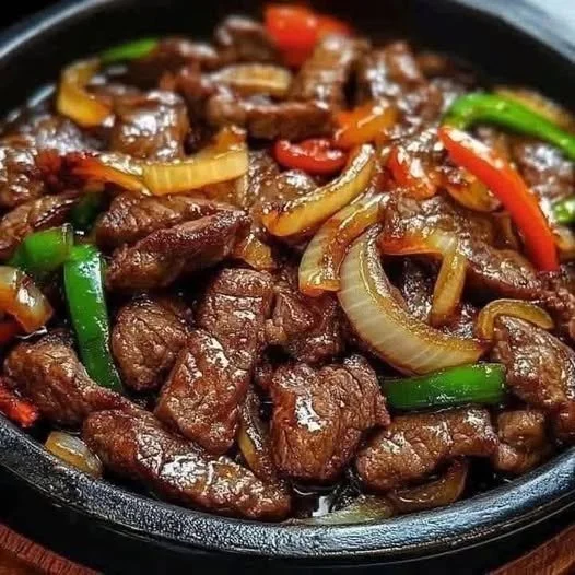 Deliciously sizzling Chinese pepper steak with onions served on a plate.