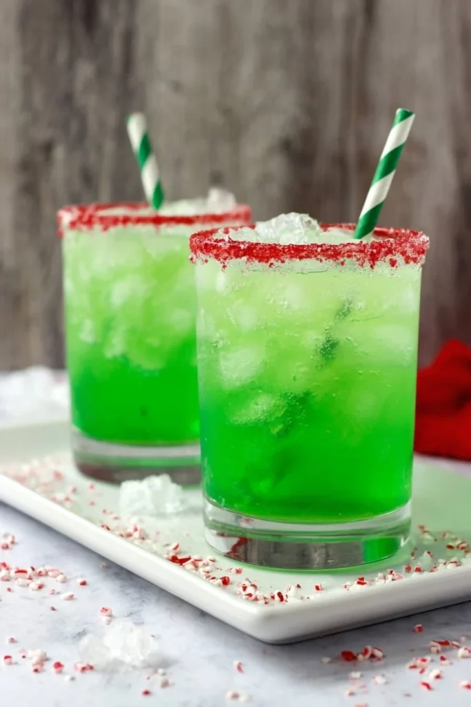 Festive Grinch Punch in a holiday-themed glass with green and red decorations.