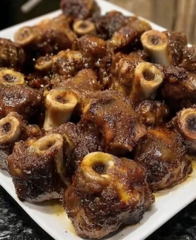 Delicious Jamaican Oxtail served with rice and peas, garnished with fresh herbs.