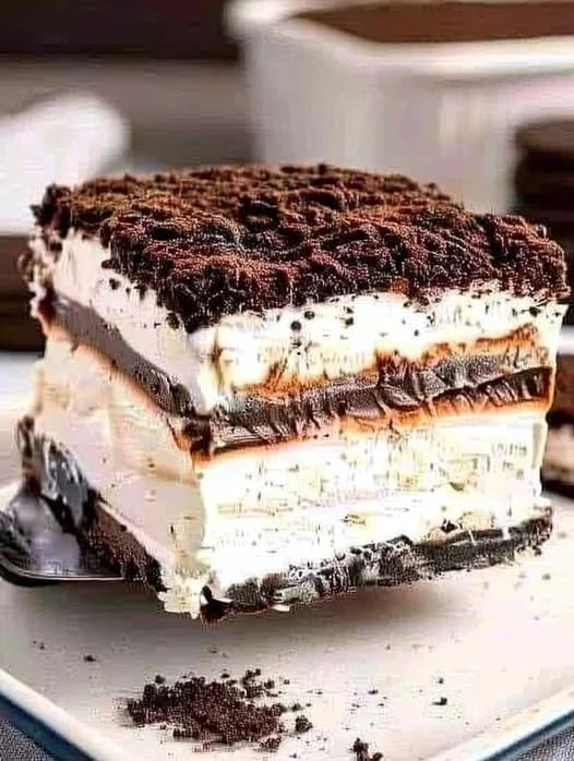 Oreo cream cheese dessert topped with crushed Oreos and chocolate drizzle